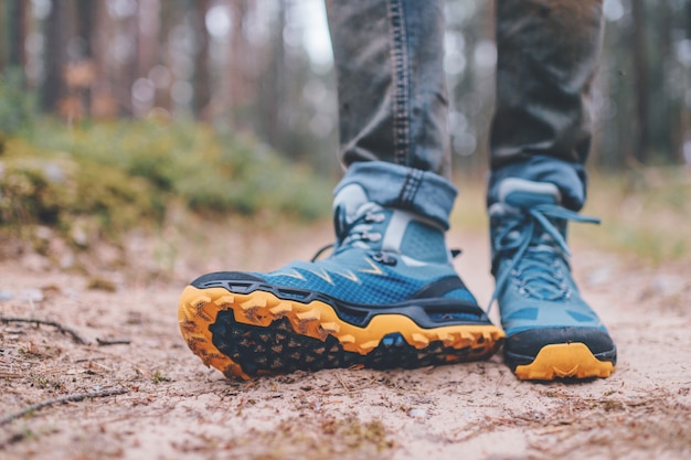 Les jambes des hommes en bottes de trekking pour les activités de plein air sur la route forestière