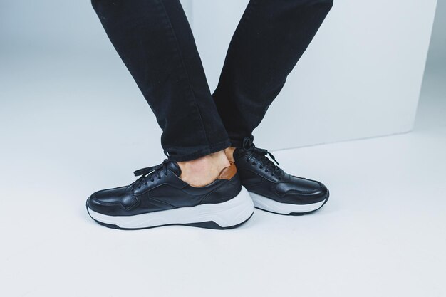 Jambes d'hommes en chaussures décontractées de couleur noire en cuir véritable hommes sur des chaussures en baskets noires Photo de haute qualité