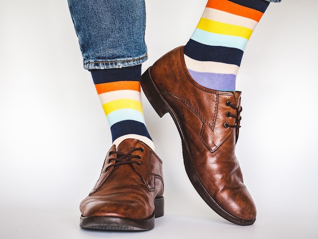 Jambes d'hommes, chaussures à la mode, jeans bleus et chaussettes longues panachées sur fond blanc,