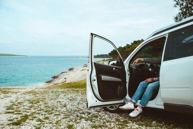 Les jambes des hommes sortent de la voiture garée en mer plage vacances d'été