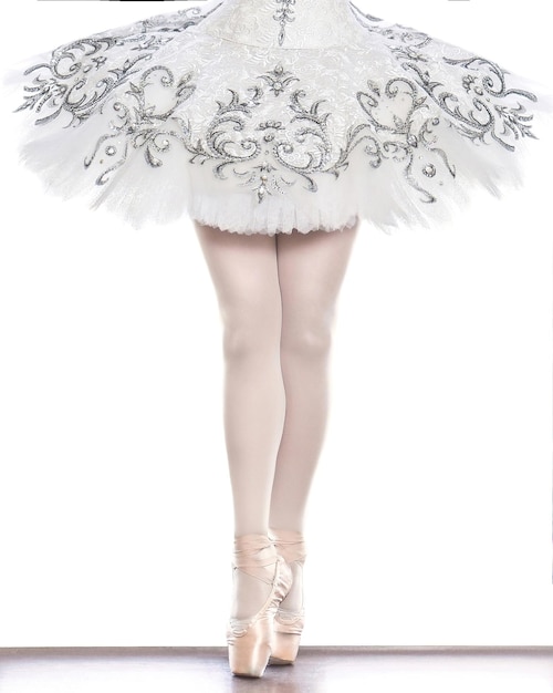 Jambes d'une jeune ballerine sur pointes en équilibre sur ses doigts dans des chaussures de ballet isolées sur fond blanc