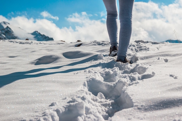 Les jambes d'une jeune femme en chaussures d'hiver sportives dans la neige profonde. Ciel bleu.