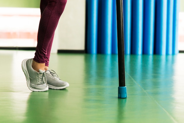 Jambes de jeune femme fit faire de l'exercice avec la barre de corps dans la salle de gym