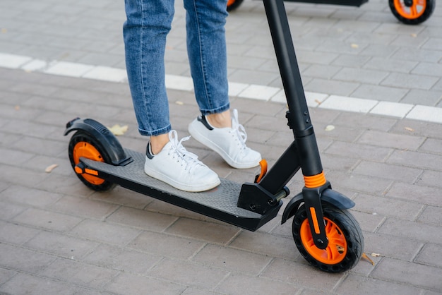 Les jambes de la jeune fille se bouchent sur un scooter électrique. Véhicule de transport moderne.