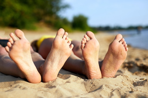 Jambes de jeunes femmes sur la plageGros plan de pieds de femme avec du sable sur la plage Vacances d'été Concept de vacances et de voyage