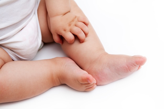 Jambes et main de bébé sur une surface blanche