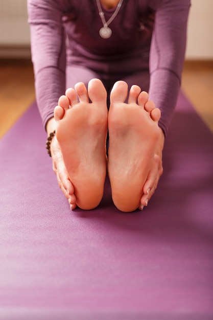 Jambes et mains d'une femme sur un tapis de yoga pratiquant des asanas. Un mode de vie sain à la maison dans l'isolement.