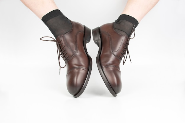 Jambes mâles en chaussettes et chaussures classiques marron sur fond blanc