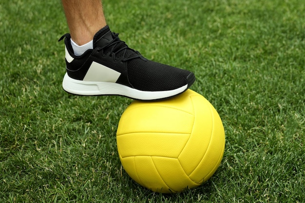 Jambes masculines en baskets et ballon de volley-ball sur l'herbe