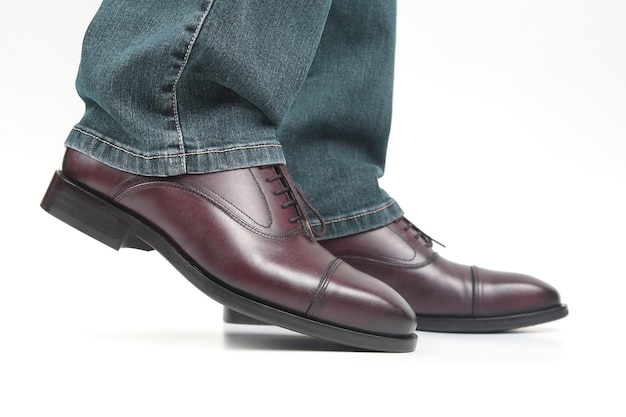 Jambes masculines en jeans et chaussures classiques marron sur fond blanc