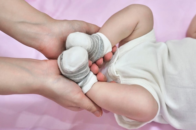 Jambes d'un nouveau-né en chaussettes blanches, le bébé est allongé sur une couverture sur le lit