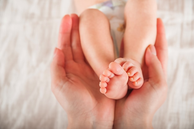 Jambes d'un nouveau-né en gros plan de mains. Pieds de bébé et espace copie. Soins aux nourrissons et coliques