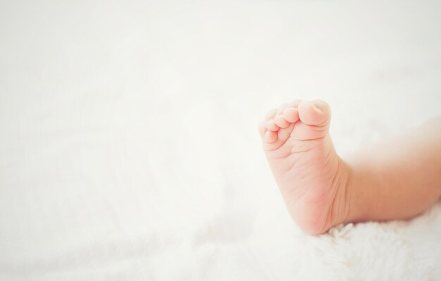 Les jambes d'un nouveau-né sur un lit blanc