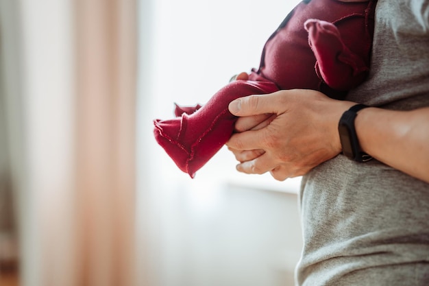 Les jambes d'un nouveau-né que papa tient. Une pose pour déposer un bébé.