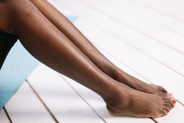 Jambes nues de femme afro-américaine gros plan fond blanc espace de copie gratuit Personne noire assise avec les jambes tendues Jambes poilues et mal rasées nouveau corps normal et mode positif