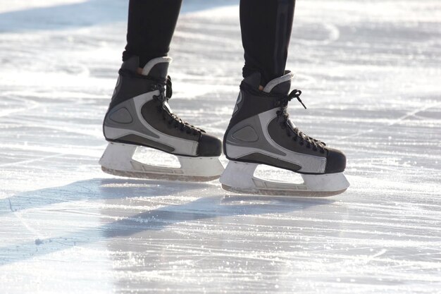 Photo jambes d'un patineur sur le patin à glace sur la patinoire de rue. sport d'hiver. passe-temps et loisirs actifs dans le sport.