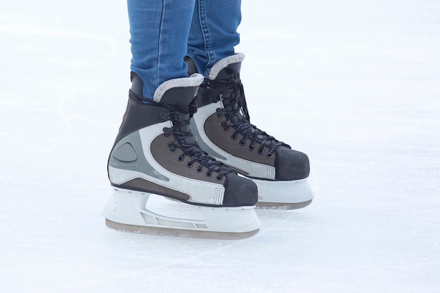 Jambes en patins patine activement sur une patinoire en gros plan. Passe-temps et sports. Vacances et activités hivernales.