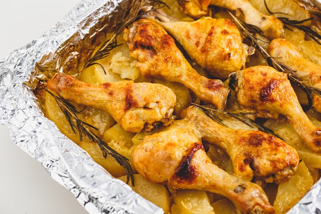 Jambes de poulet appétissantes cuites au four avec pommes de terre et romarin en papillote.