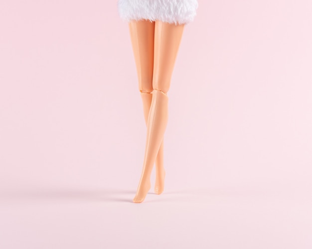 Jambes de poupée fille sur rose pastel