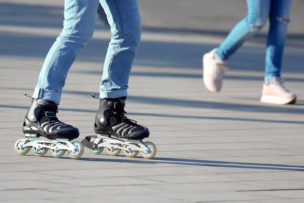 Jambes roulant sur patins à roulettes en arrière-plan personne qui marche. Divertissement et loisirs. Sports et Loisirs des adolescents