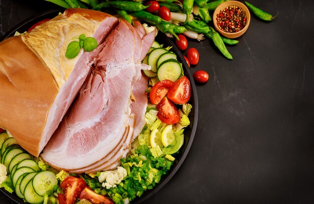 Jambon entier coupé avec des légumes et des herbes