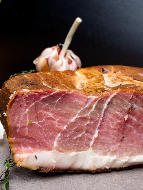 Jambon fumé sur une table en pierre avec ajout d'herbes aromatiques fraîches et d'épices Produit naturel de la ferme biologique produit selon des méthodes traditionnelles