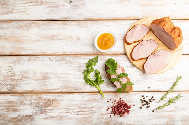 Jambon de porc fumé sur planche à découper sur fond de bois blanc Vue de dessus copie espace