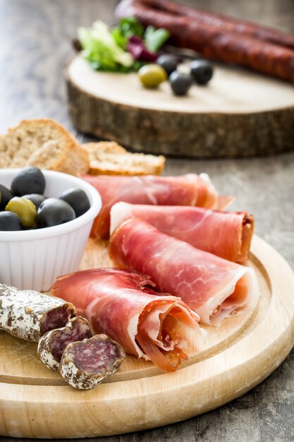 Photo jambon serrano espagnol, olives et saucisses sur bois