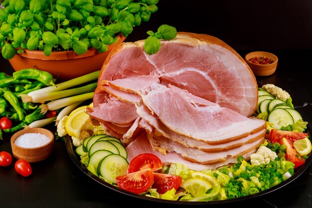 Jambon tranché avec des légumes frais sur une assiette.