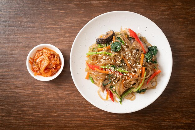 Photo japchae ou vermicelles coréens sautés aux légumes et au porc garnis de sésame blanc - style de cuisine traditionnelle coréenne