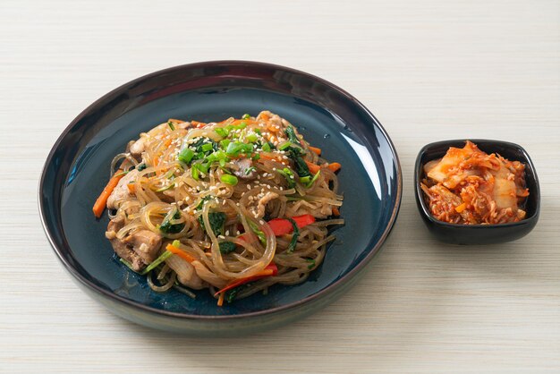 Photo japchae ou vermicelles coréens sautés aux légumes et au porc garnis de sésame blanc - style de cuisine traditionnelle coréenne