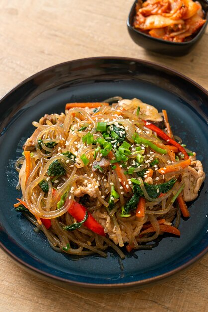 japchae ou vermicelles coréens sautés aux légumes et au porc garnis de sésame blanc - style de cuisine traditionnelle coréenne