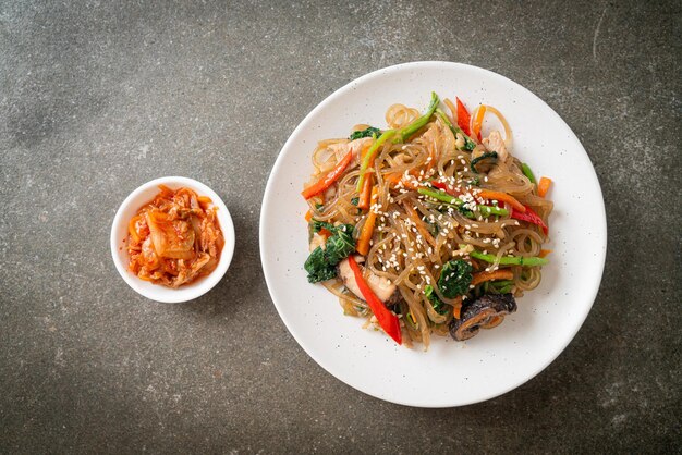 Photo japchae ou vermicelles coréens sautés aux légumes et au porc garnis de sésame blanc - style de cuisine traditionnelle coréenne