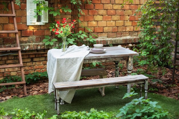 Jardin en été avec salon de jardin en bois de terrasse table et banc en bois