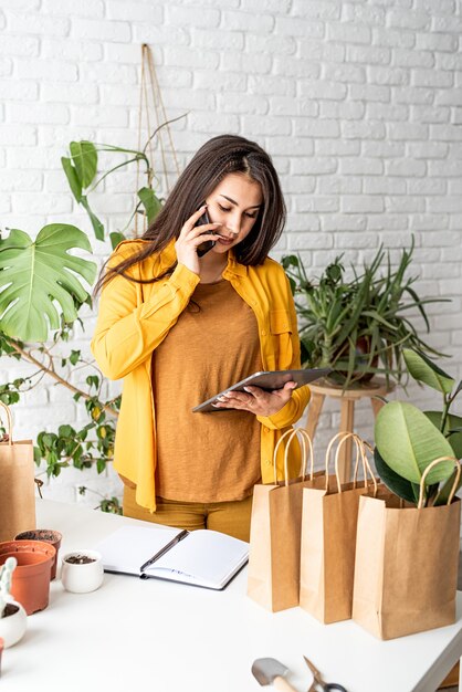 Jardinage domestique. Petite entreprise. Jardinier femme travaillant sur tablette numérique et passer un appel