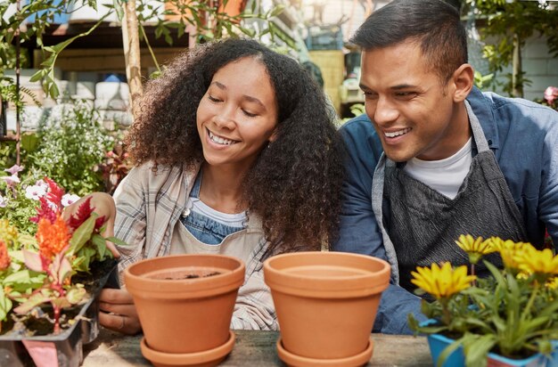 Jardiner des fleurs et un couple travaillant sur des plantes dans une pépinière extérieure de jardin et une serre durable pour un magasin de boutique