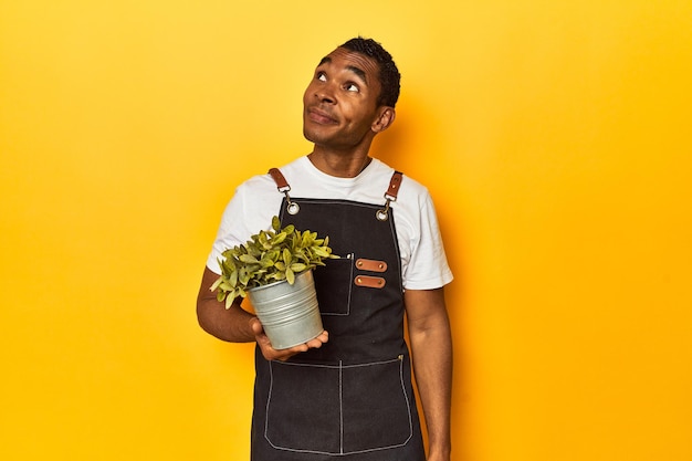 Photo jardinier afro-américain avec un studio de plantes jaunes rêvant d'atteindre des objectifs et des buts