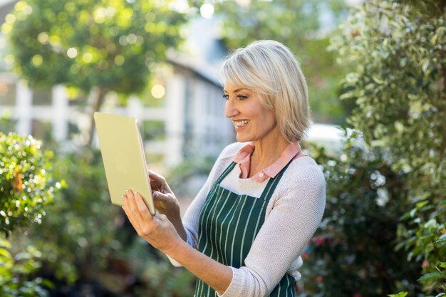 Jardinier à l'aide d'une tablette numérique à l'extérieur de la serre