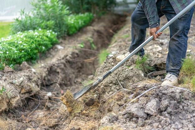 Le jardinier creuse le sol avec son équipement pour le jardinage et prépare la terre pour la plantation.