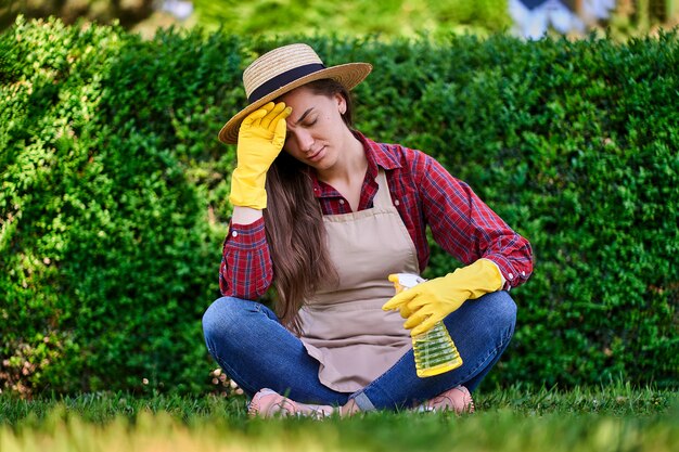 Photo jardinier fatigué femme assise dans l'herbe