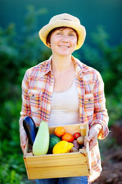 Jardinier femme d&#39;âge mûr tenant une caisse en bois avec des légumes biologiques frais de la ferme