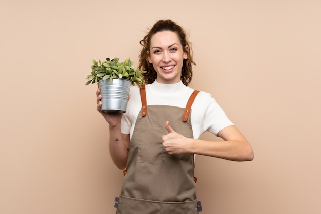 Jardinier femme tenant une plante avec les pouces vers le haut parce que quelque chose de bien s'est produit