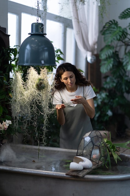 Jardinier de fille prenant soin de la plante aquatique dans la serre tenant la plante d'intérieur sous le bain avec de l'eau