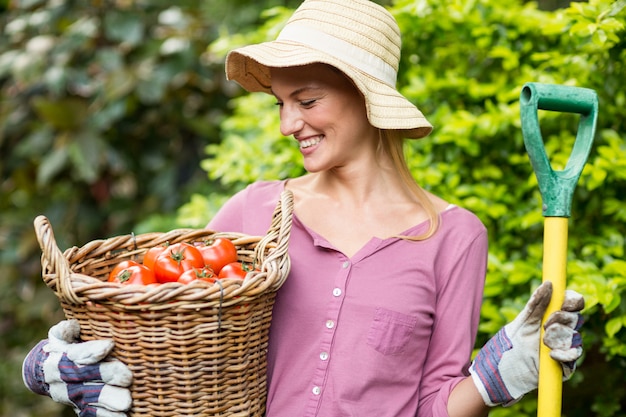 Jardinier heureux tenant le panier de tomates et l'outil de travail