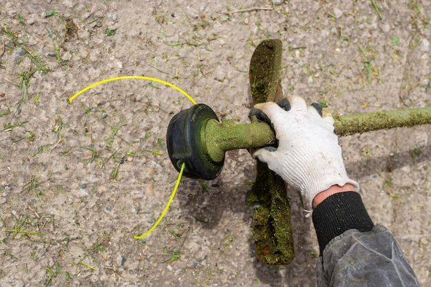 Le jardinier a installé une nouvelle ligne de capron pour couper l'herbe sur la tondeuse à gazon Coupe de l'herbe d'été