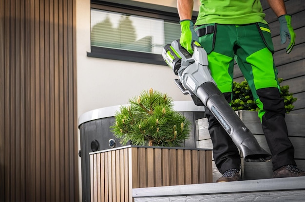 Le jardinier nettoie avec un souffleur d'air électrique portatif