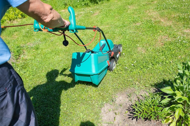 Jardinier principal tondant sa pelouse verte dans le jardin Homme travaillant sur la pelouse coupant l'herbe avec une tondeuse à gazon l'homme tond l'herbe avec une tondeuse électrique Travail physique et travail à temps partiel