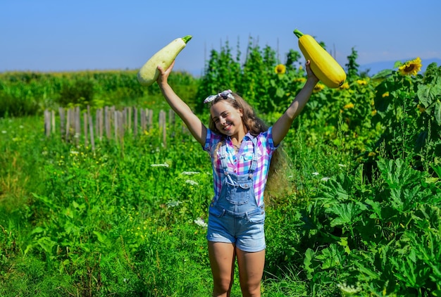 Jardinier professionnel adolescente sur la ferme de squash vacances d'été riche récolte et agriculture enfance heureuse enfant rétro tenir un enfant sain de moelle végétale cultiver des courgettes dans l'agriculture de jardin