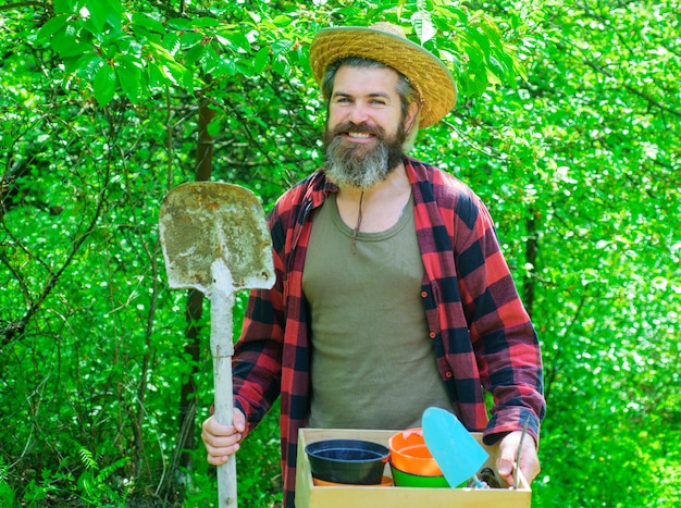 Jardinier professionnel. Heureux homme barbu dans le jardin. Eco-ferme. Mâle avec des outils de jardinage.