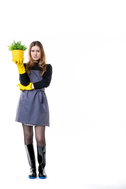 Jardinière vue de face en gants jaunes tenant une petite plante sur blanc